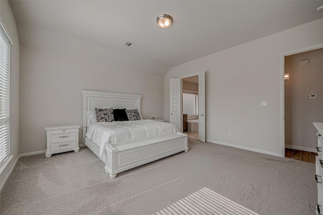 bedroom with vaulted ceiling, baseboards, visible vents, and light colored carpet