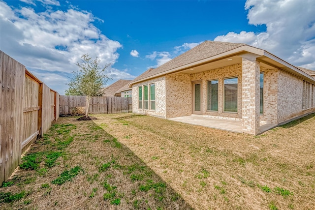 back of property featuring a patio area, brick siding, a fenced backyard, and a lawn