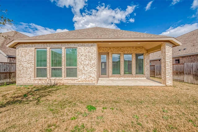 rear view of property with a patio area, a fenced backyard, a yard, and brick siding