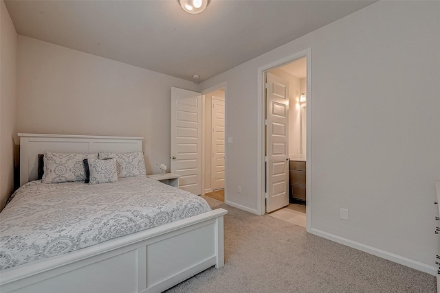 bedroom with light carpet, ensuite bathroom, and baseboards