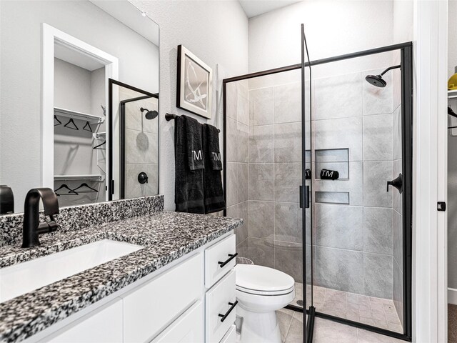 bathroom with tile patterned flooring, vanity, an enclosed shower, and toilet