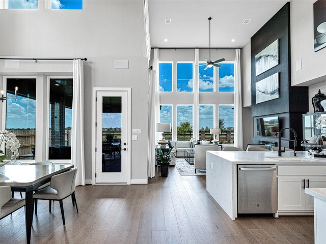 kitchen with dark hardwood / wood-style floors, white cabinetry, hanging light fixtures, a high ceiling, and stainless steel dishwasher