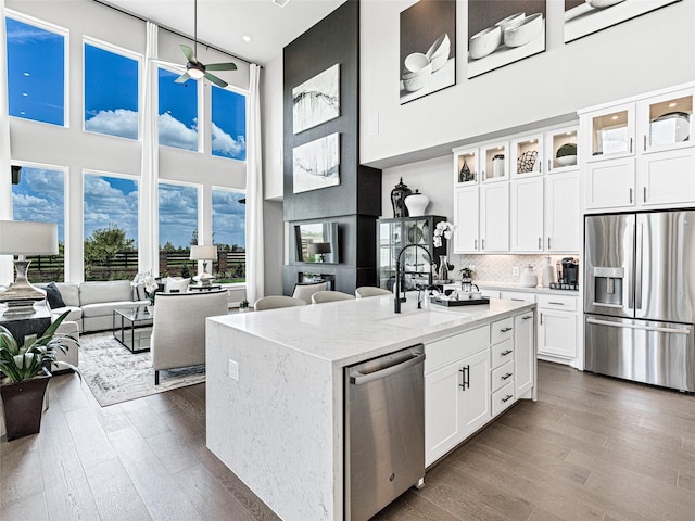 kitchen with sink, hanging light fixtures, stainless steel appliances, light stone countertops, and white cabinets