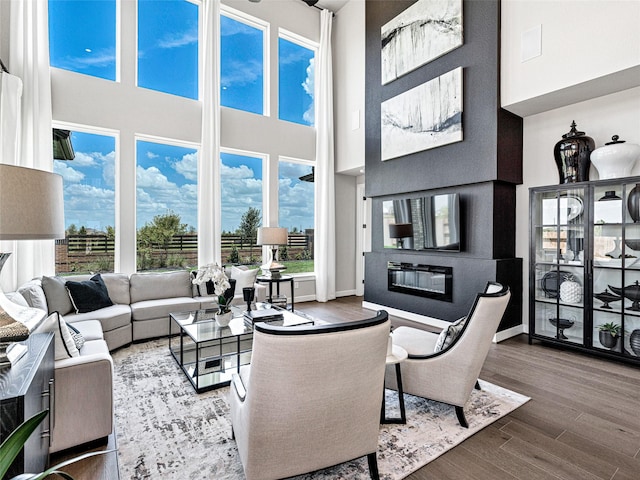 living room featuring hardwood / wood-style flooring, a healthy amount of sunlight, and a towering ceiling