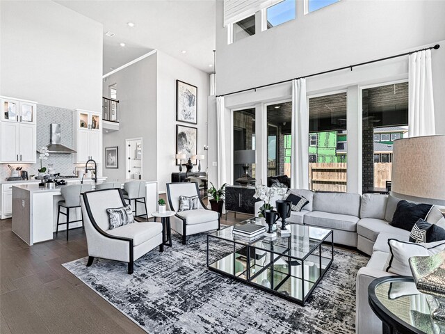 living room with dark wood-type flooring, sink, and a high ceiling