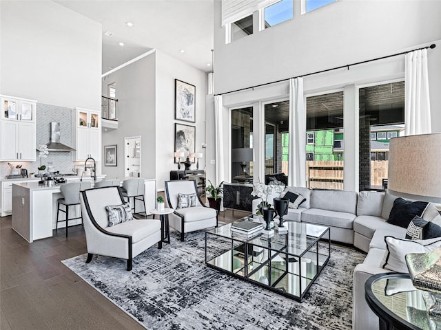 living room featuring dark hardwood / wood-style flooring, sink, and a high ceiling