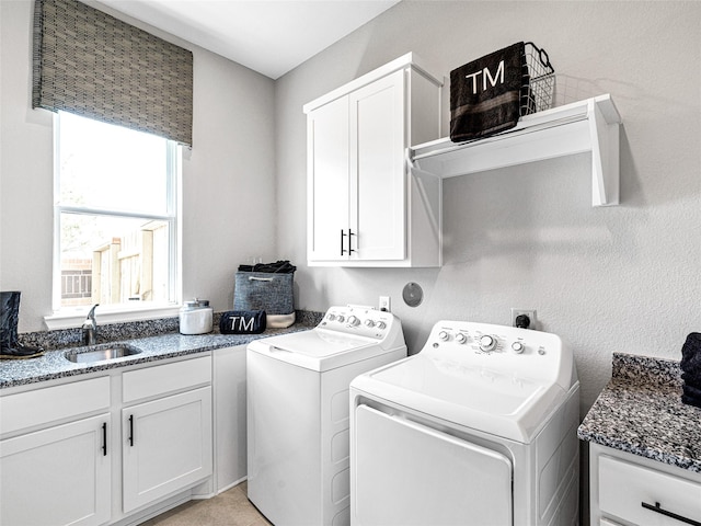 clothes washing area with cabinets, washing machine and dryer, and sink