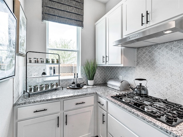 kitchen featuring white cabinetry, backsplash, light stone countertops, and black gas cooktop