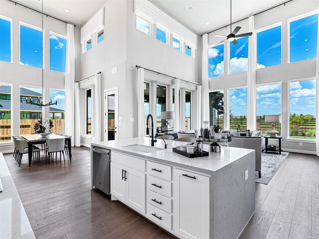 kitchen with hanging light fixtures, white cabinetry, sink, and light stone counters