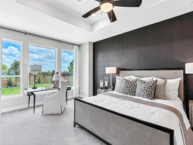 carpeted bedroom with ceiling fan and a tray ceiling