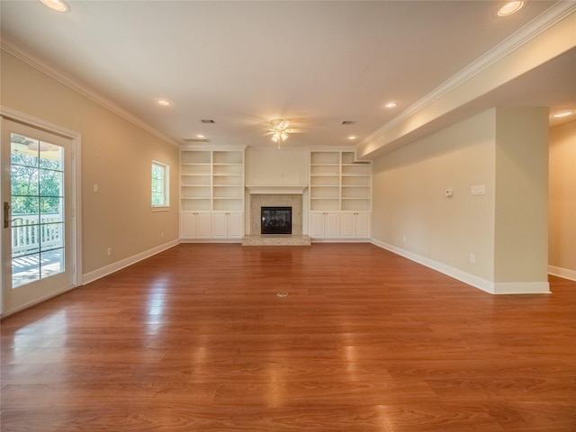 unfurnished living room featuring ornamental molding, wood-type flooring, ceiling fan, and built in shelves