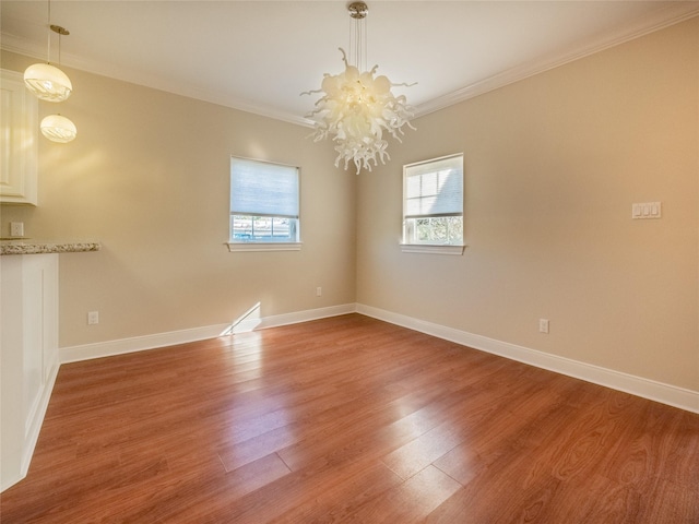 empty room featuring crown molding, hardwood / wood-style floors, and a chandelier