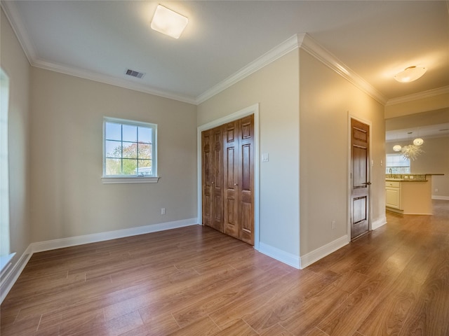 empty room with crown molding and light hardwood / wood-style flooring