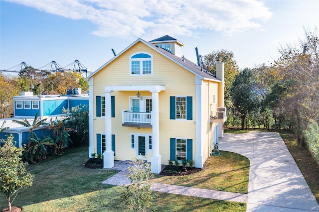 view of front of home featuring a garage, a front yard, and a balcony