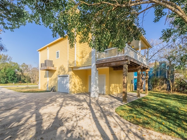 rear view of property featuring a garage, a yard, and a deck