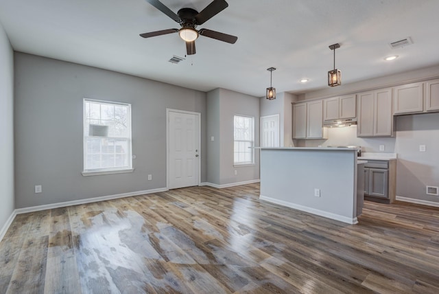 kitchen with hanging light fixtures, gray cabinets, a kitchen island, ceiling fan, and hardwood / wood-style floors