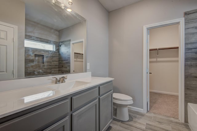 bathroom featuring tiled shower, vanity, and toilet