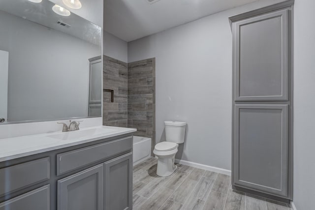 full bathroom with tiled shower / bath, vanity, and toilet