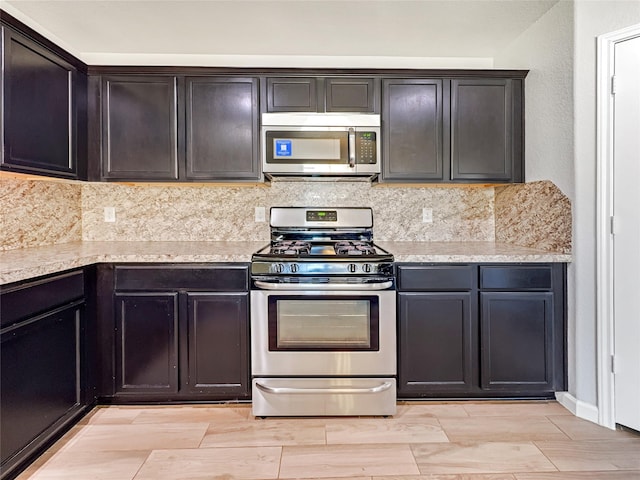 kitchen featuring stainless steel appliances, light stone countertops, and backsplash