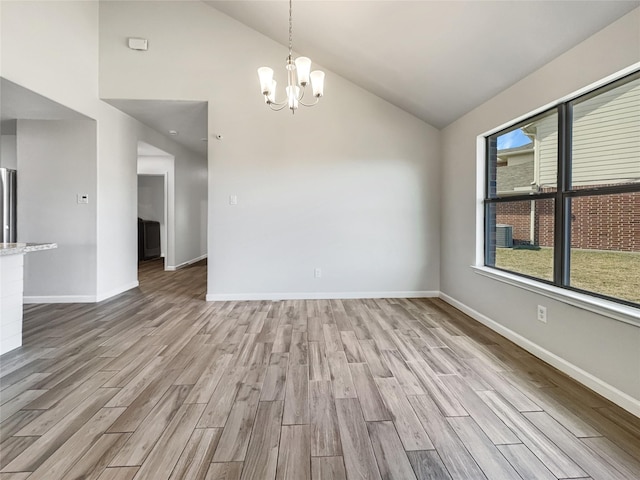 empty room featuring lofted ceiling, an inviting chandelier, and light hardwood / wood-style flooring