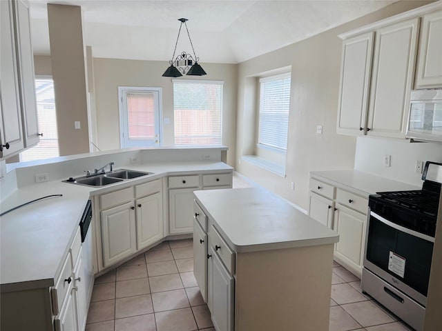 kitchen featuring sink, stainless steel gas range oven, decorative light fixtures, a kitchen island, and white cabinets