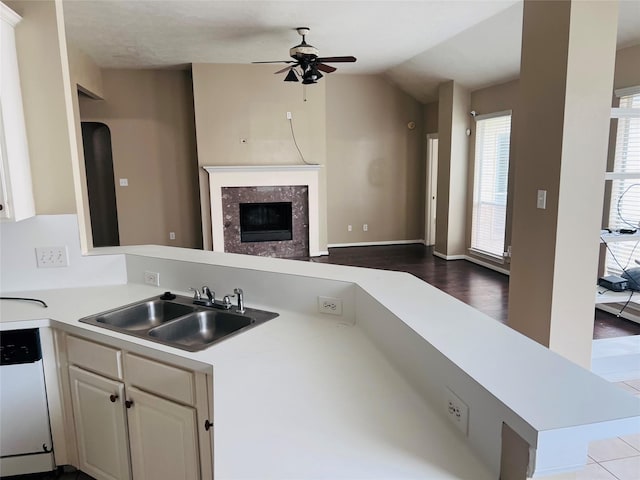 kitchen with lofted ceiling, sink, dishwashing machine, a high end fireplace, and kitchen peninsula