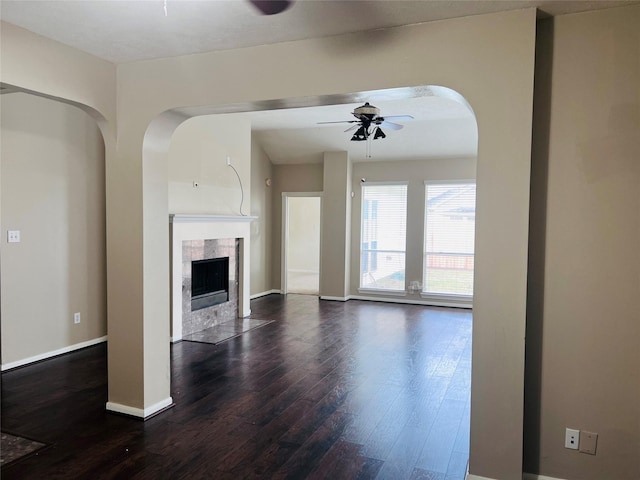 unfurnished living room featuring ceiling fan, dark hardwood / wood-style floors, and a fireplace