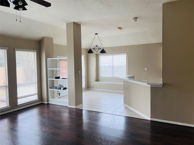 unfurnished dining area with ceiling fan, vaulted ceiling, hardwood / wood-style floors, and a textured ceiling