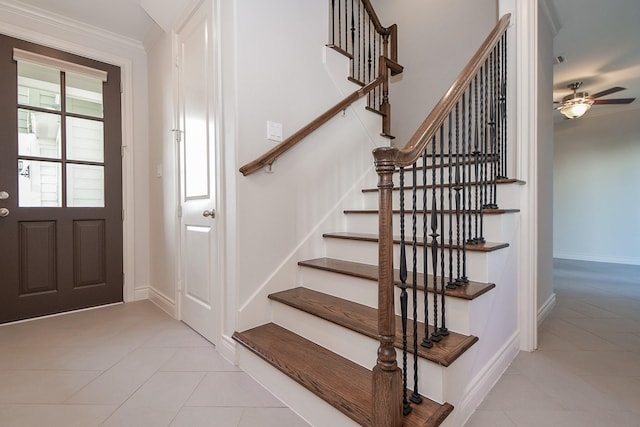 tiled foyer entrance with ornamental molding and ceiling fan