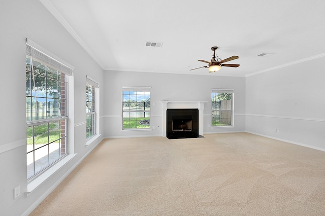 unfurnished living room featuring light colored carpet, ornamental molding, and plenty of natural light