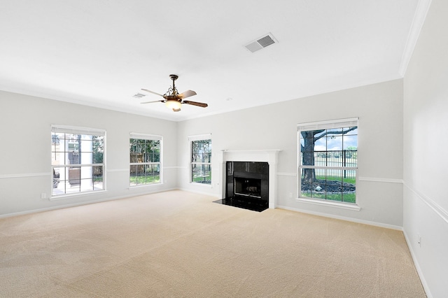 unfurnished living room with a tiled fireplace, crown molding, light carpet, and ceiling fan