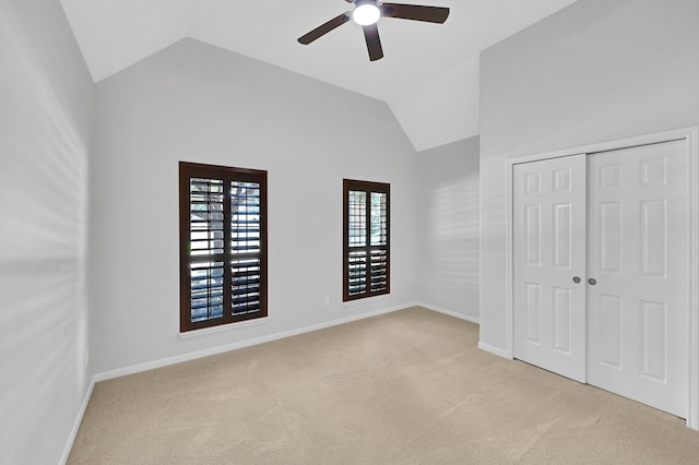 unfurnished bedroom featuring high vaulted ceiling, light colored carpet, a closet, and ceiling fan