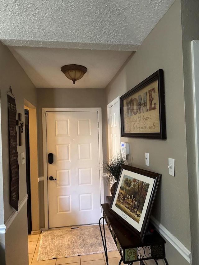 doorway to outside featuring a textured ceiling and light tile patterned flooring