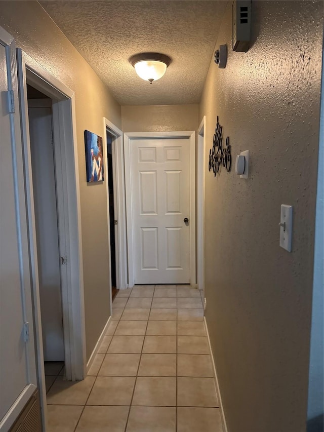 hallway featuring light tile patterned flooring and a textured ceiling