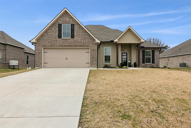 view of property featuring a garage, a front lawn, and central air condition unit