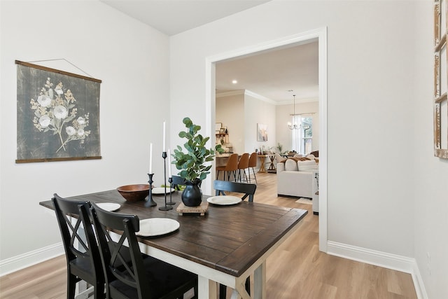 dining area with an inviting chandelier, ornamental molding, and light wood-type flooring