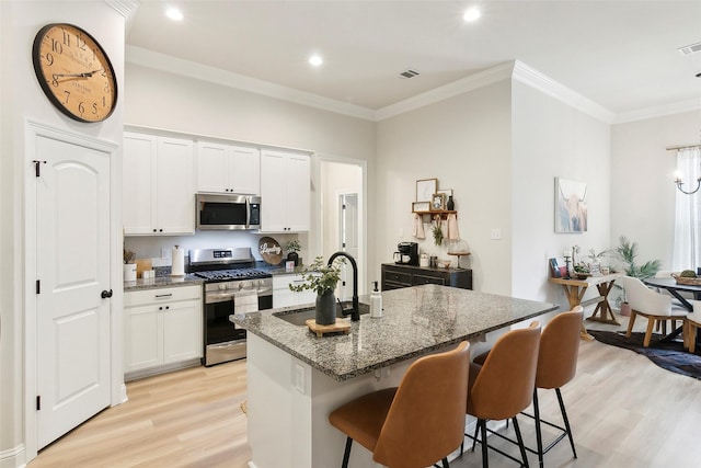 kitchen featuring an island with sink, appliances with stainless steel finishes, sink, and white cabinets