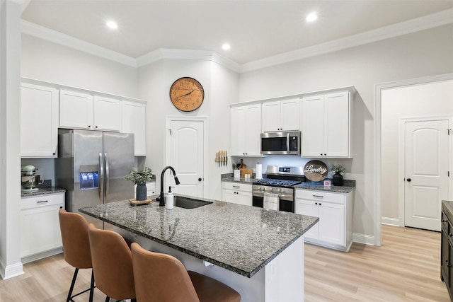 kitchen featuring appliances with stainless steel finishes, white cabinetry, an island with sink, sink, and a kitchen breakfast bar