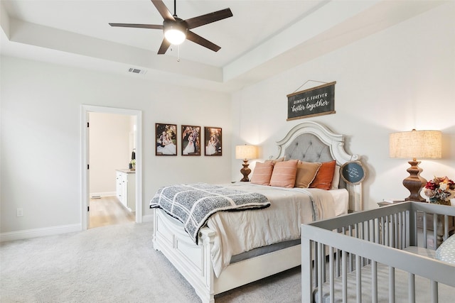 bedroom featuring light carpet and a tray ceiling