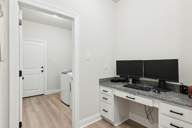 office space featuring built in desk, washer and clothes dryer, and light hardwood / wood-style floors