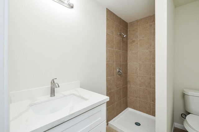 bathroom with vanity, toilet, and a tile shower