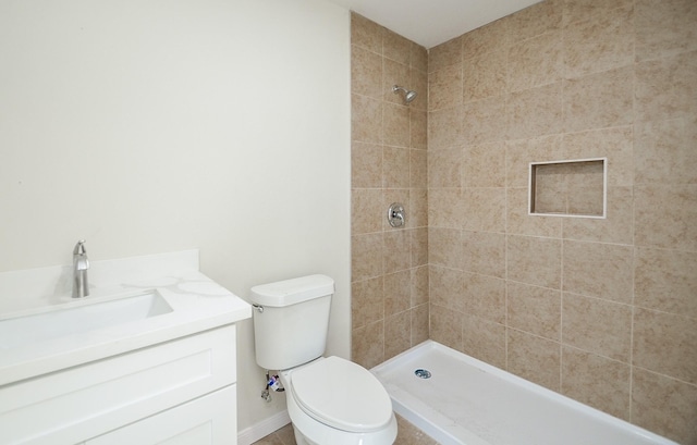 bathroom featuring vanity, tiled shower, and toilet