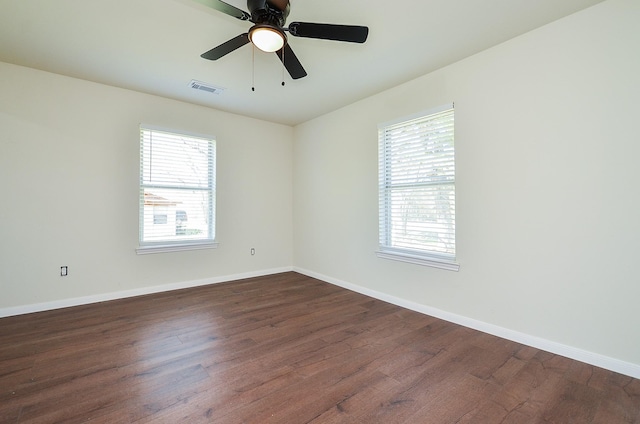 unfurnished room featuring a healthy amount of sunlight, dark wood-type flooring, and ceiling fan