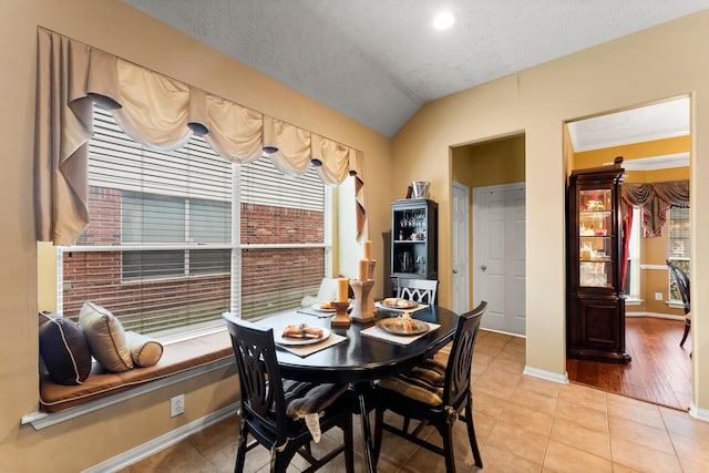 tiled dining area with vaulted ceiling and a textured ceiling