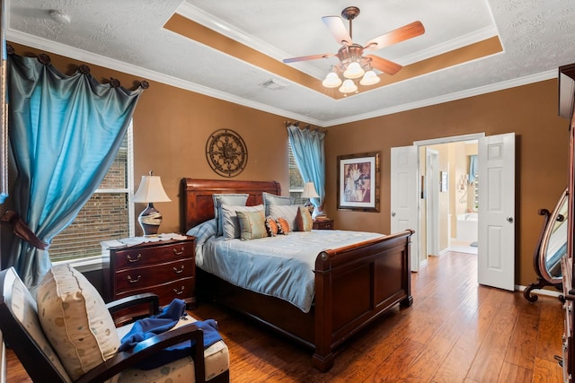 bedroom featuring dark hardwood / wood-style flooring, ornamental molding, a raised ceiling, and a textured ceiling