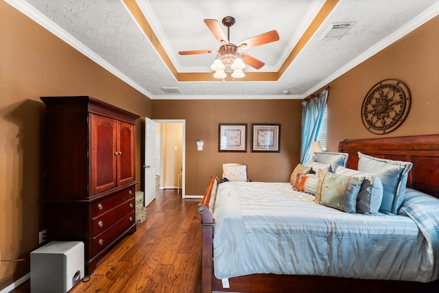 bedroom featuring a raised ceiling, crown molding, dark hardwood / wood-style floors, and a textured ceiling