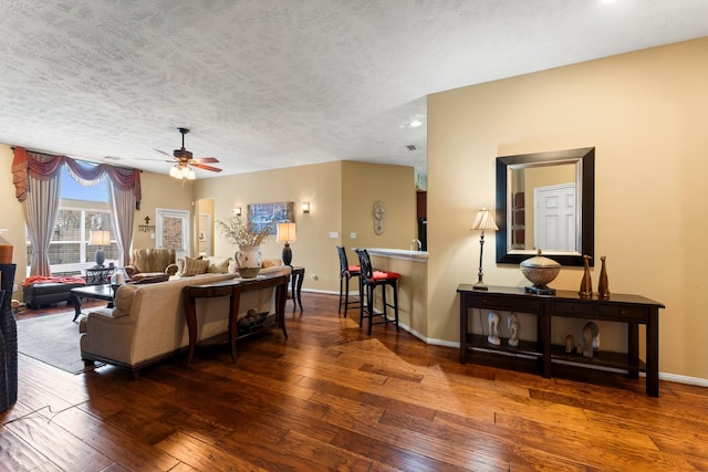 living room with dark wood-type flooring, ceiling fan, and a textured ceiling