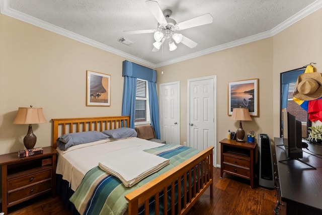 bedroom with two closets, ornamental molding, ceiling fan, dark wood-type flooring, and a textured ceiling