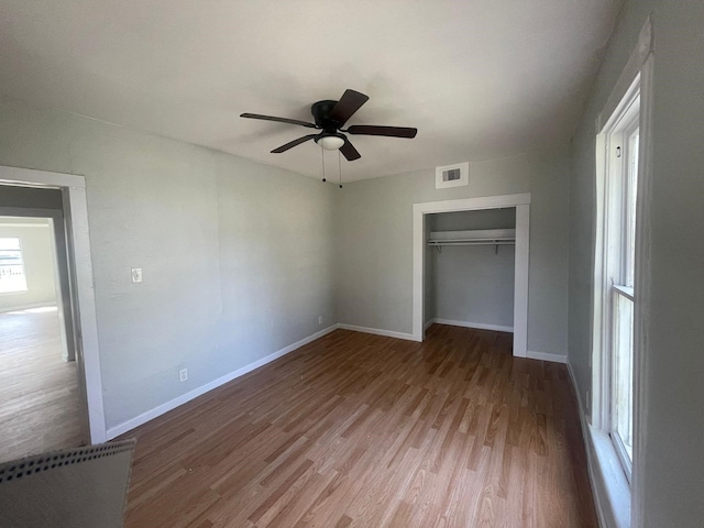 unfurnished bedroom featuring hardwood / wood-style floors, a closet, and ceiling fan