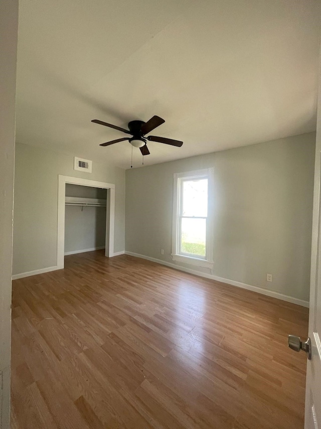 unfurnished bedroom with ceiling fan, light wood-type flooring, and a closet